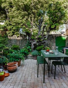 an outdoor patio with tables and chairs surrounded by trees, plants and potted plants