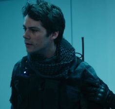 a young man wearing a scarf and jacket in a room with blue light from the window