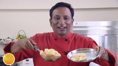 a man in a red chef's coat is holding a metal bowl with food on it