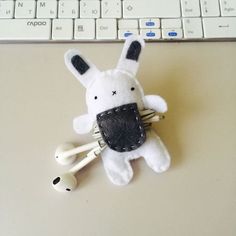 a white stuffed animal sitting on top of a desk next to headphones and a keyboard