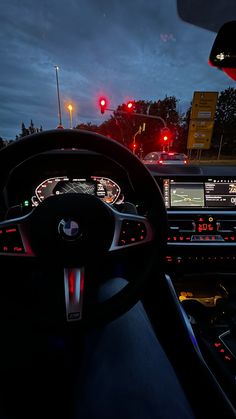 the interior of a car at night with red traffic lights and dash lights on it