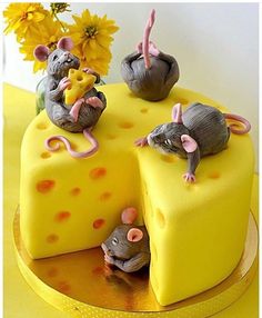 a cake with three mice sitting on top of it and yellow flowers in the background