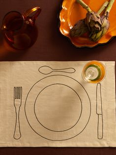 a place mat with a knife, fork and spoon on it next to an orange plate