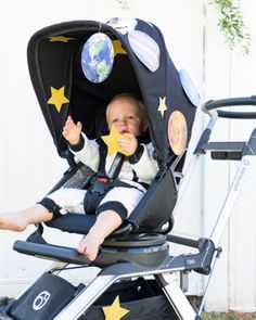 a small child sitting in a stroller with stars on it's side and the earth above his head