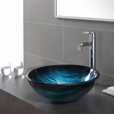 a glass bowl sink sitting on top of a counter next to a faucet