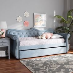 a blue daybed sitting on top of a wooden floor next to a white dresser