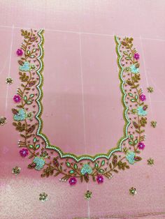 an elaborate necklace is displayed on a pink surface with gold and green jewels around it