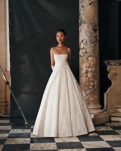 a woman in a white wedding dress standing on a black and white checkered floor