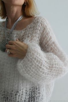 a woman wearing a white sweater and necklace