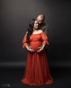 a man and woman standing next to each other in front of a dark background with their hands on the belly