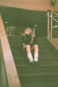 a woman sitting on the stairs in front of a brick building