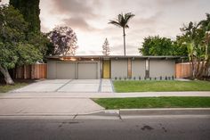 a modern house with palm trees in the back ground and grass on the front lawn