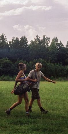 two people are playing frisbee in the grass with trees in the back ground