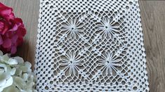 a crocheted doily next to flowers on a table