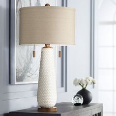 a white lamp sitting on top of a table next to a vase filled with flowers