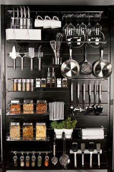 an organized kitchen with pots, pans and utensils hanging on the wall