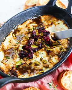 an iron skillet filled with baked bread and cranberry sauce on a red cloth