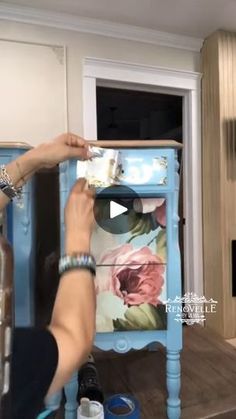 a person painting a blue table with flowers on it