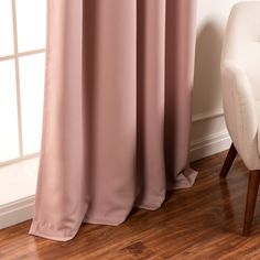 a white chair sitting in front of a window next to a pink drape curtain