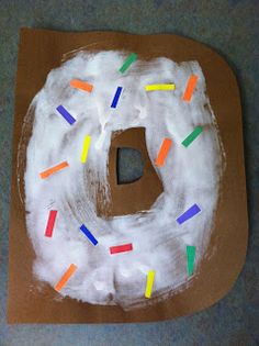 a doughnut with icing and sprinkles sitting on top of a piece of brown paper