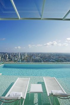 an outdoor swimming pool with lounge chairs overlooking the city