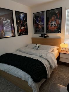 a bedroom with two posters on the wall and a bed in front of it,