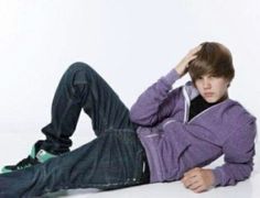 a young man laying on the ground with his hands behind his head, wearing a purple jacket and jeans