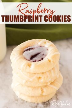 raspberry thumbprint cookies stacked on top of each other in front of a bottle of milk