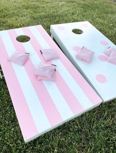 two pink and white striped cornhole boards with bows on them sitting in the grass