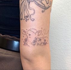 a woman's arm with tattoos on it, including an image of a dog and a cat