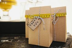 two brown bags tied with twine and measuring tape on top of a wooden table