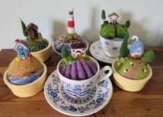 small pots with plants in them sitting on a wooden table next to plates and cups