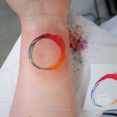 a woman's wrist with a colorful circle tattoo on her left arm and the word love written across it