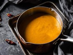 a pan filled with soup sitting on top of a table next to some chili peppers