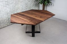 a wooden table sitting in front of a brick wall next to a potted plant