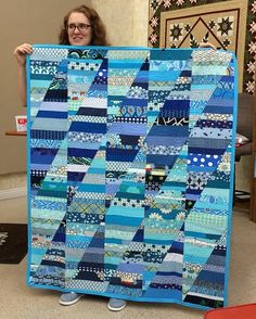 a woman holding up a very large blue quilt