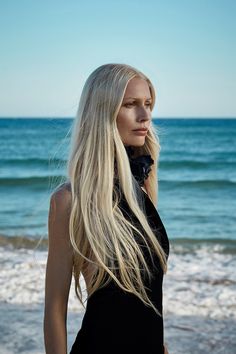 a woman with long blonde hair standing in front of the ocean on her instagram page