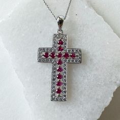 Materials: 14k White Gold Gemstone: Genuine Ruby and Diamond Total Ruby Carat Weight: 0.48 ct. Total Diamond Carat Weight: 0.45 ct. Pendant Diameter: 32mm x 17mm Diamond Clarity: SI 1-2 Diamond Color: I color Description: This listing is for the pendant only, the necklace is not included for the price. However if you would like to purchase the necklace with the pendant, feel free to message me. These are genuine rubies and diamonds, not lab grown. The stones have not been treated in any way. 56 diamonds totaling 0.45 ct and 12 rubies totaling 0.45 ct.  This beautiful piece will not tarnish in the shower and will not irritate the skin. It will arrive in a jewelry box, with a jewelry bag for traveling. Perfect for gift giving! Feel free to message me with any questions! Red Round Cut Jewelry With Pave Setting, Red Round Cut Pave Set Jewelry, Anniversary Diamond Cross Pendant Necklace With Pave Setting, Red Pave Setting Jewelry Gift, Silver Ruby Jewelry With Pave Setting, Red Pave Setting Jewelry For Gift, Cross-shaped Prong Set Diamond Necklace Gift, Oval Pave Setting Diamond Necklace Gift, Diamond Cross Pendant Necklace With Pave Setting