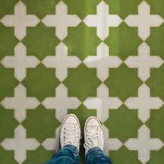 a person standing in front of a green and white tiled floor with their feet on the ground