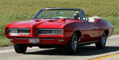 a red convertible car driving down the road