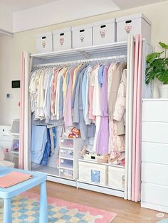 an organized closet with clothes hanging on the walls and drawers, along with a blue table