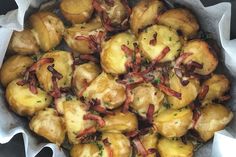 a bowl filled with potatoes and bacon on top of wax paper wrapped in napkins