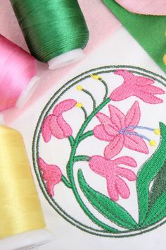 sewing supplies including thread, spools and scissors on a white cloth with pink flowers