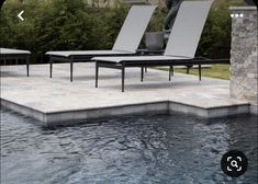 two lounge chairs sitting on top of a swimming pool