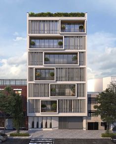 an apartment building with many windows and plants on the top floor, in front of a parking lot