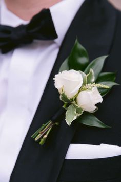 a man in a tuxedo wearing a boutonniere with white roses