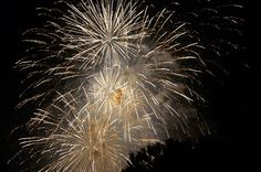 fireworks are lit up in the night sky with dark skies and trees behind them,