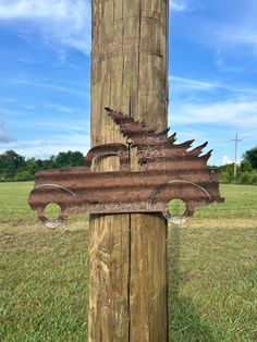 an old rusted metal sign on a wooden pole in the middle of a field