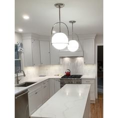 a kitchen with white cabinets and marble counter tops, stainless steel appliances and an island in the middle