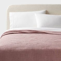 a bed with white pillows and pink bedspread